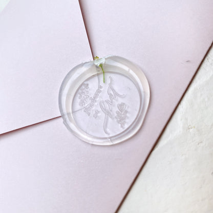 Průhledná svatební pečeť s květinou a textem "budeme se brát" na růžové obálce a bílém podkladu detail z profilu