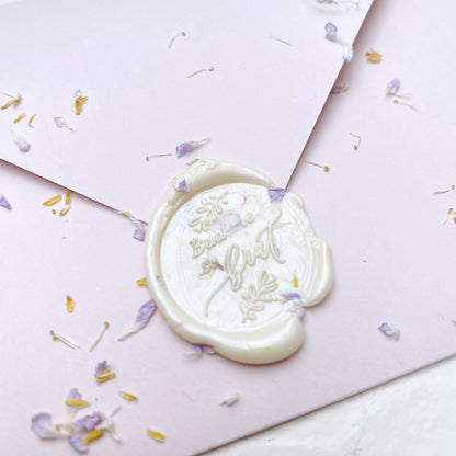 Bílá hotová pečeť "budeme se brát" na svatební oznámení na růžové obálce s květinami detail zeshora