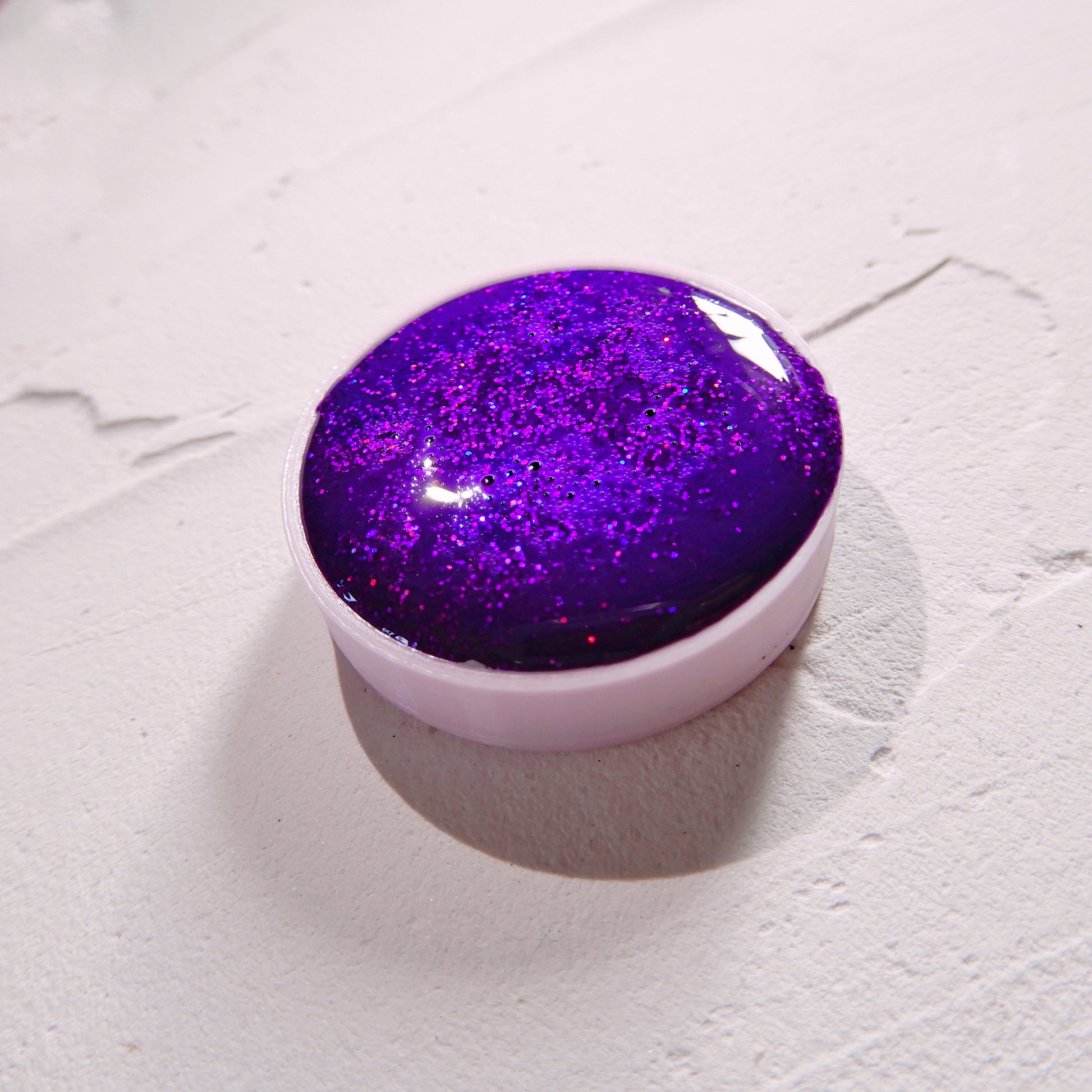 Ručně vyráběná akvarelová barva ve fialovém holografickém provedení na bílém podkladu zeshora