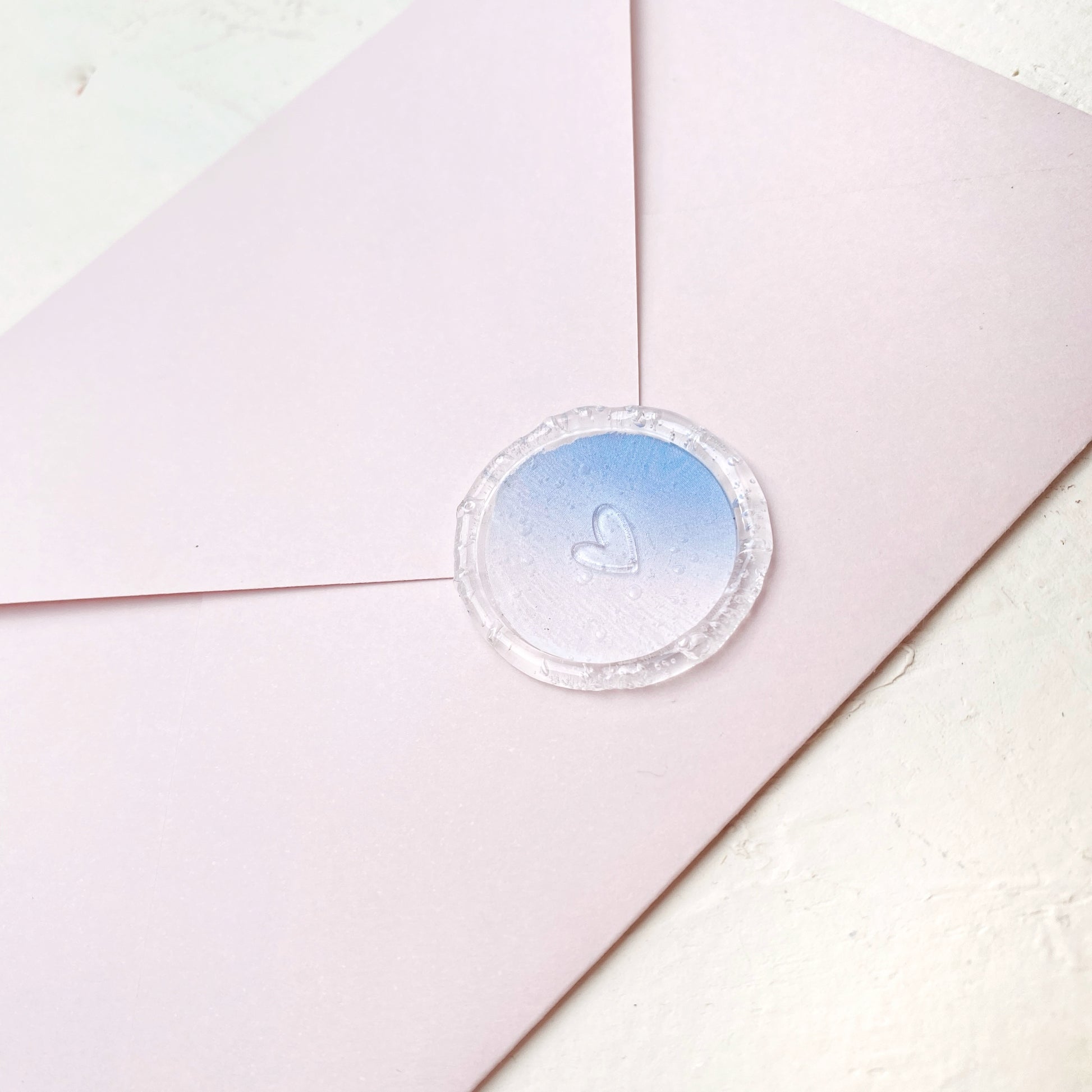 Hotová pečeť na svatební oznámení Srdíčko plné s modro růžovým podkladem na růžové obálce detail z profilu