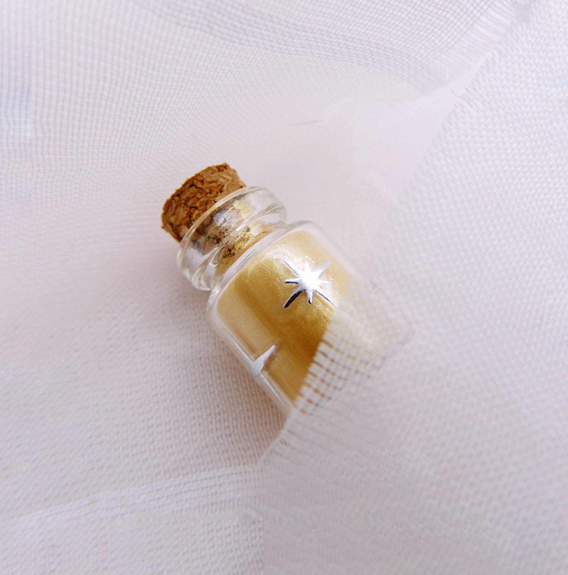 Zlatý pigmentový prášek ve skleněné lahvičce detail z profilu