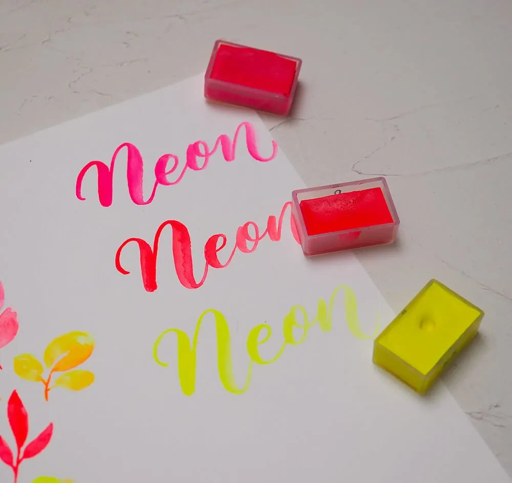 Neonové akvarelové barvy: růžová, oranžová a žlutá na akvarelovém papíru zeshora