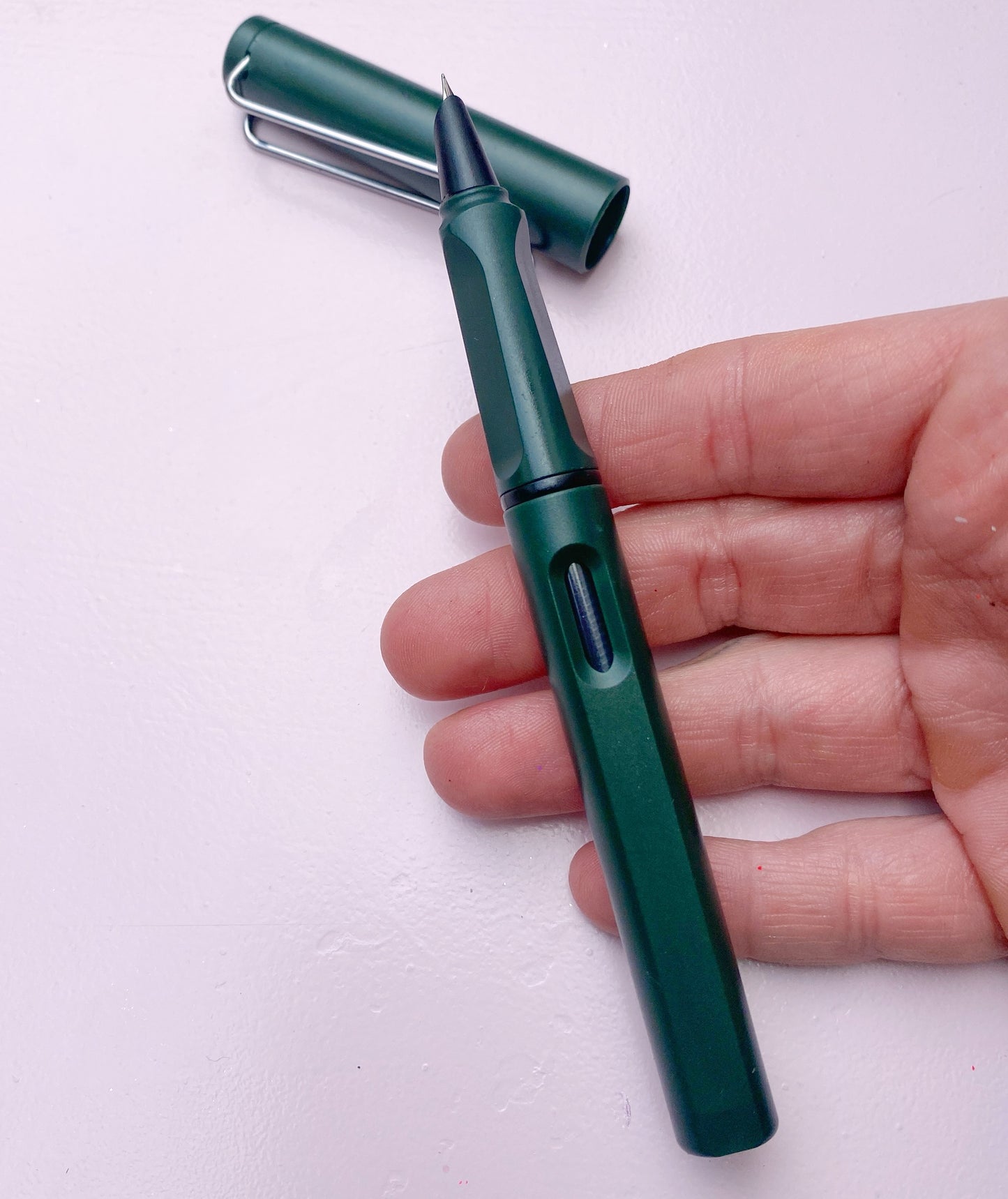 Tmavě zelené plnící pero otevřené na ruce zeshora