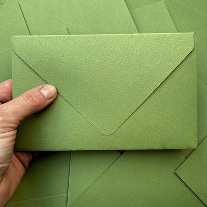 Obálka ze zeleného, vysokogramážního papíru s ražbou v ruce zeshora